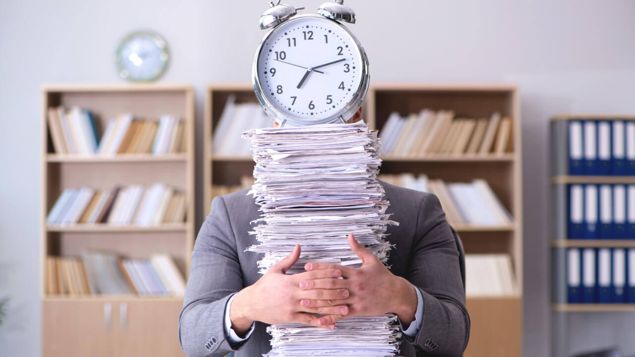 Eine Person mit einem Stapel Dokumente auf der eine Uhr steht.